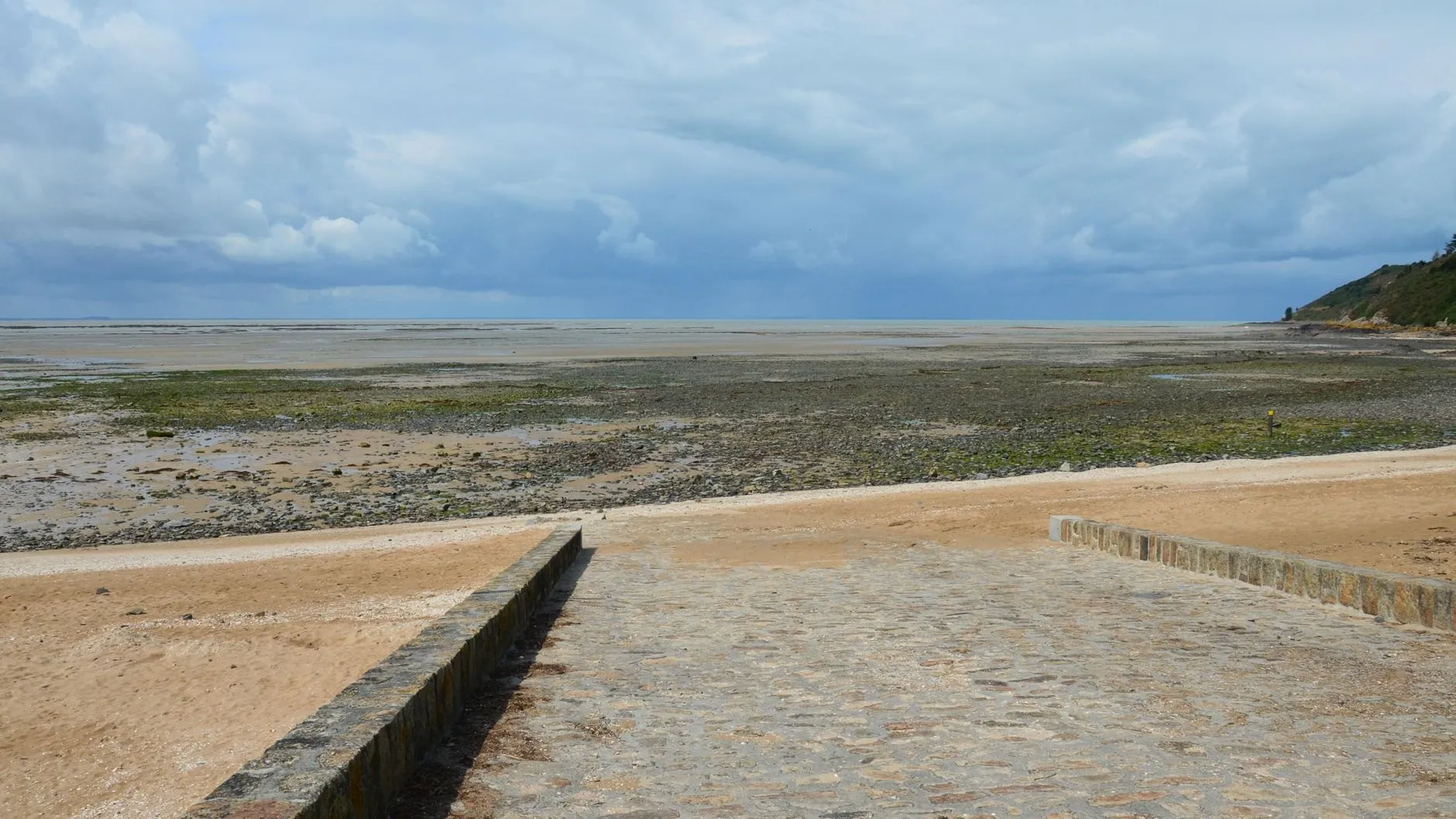 A stone slipway running down to wide sand flats at low tide